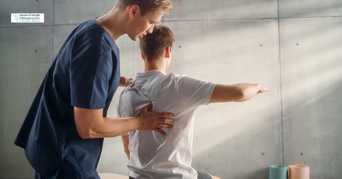 Person holding lower back in pain during chiropractic consultation